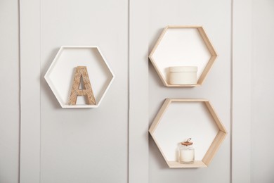 Photo of Honeycomb shaped shelves with decorative elements on white wall