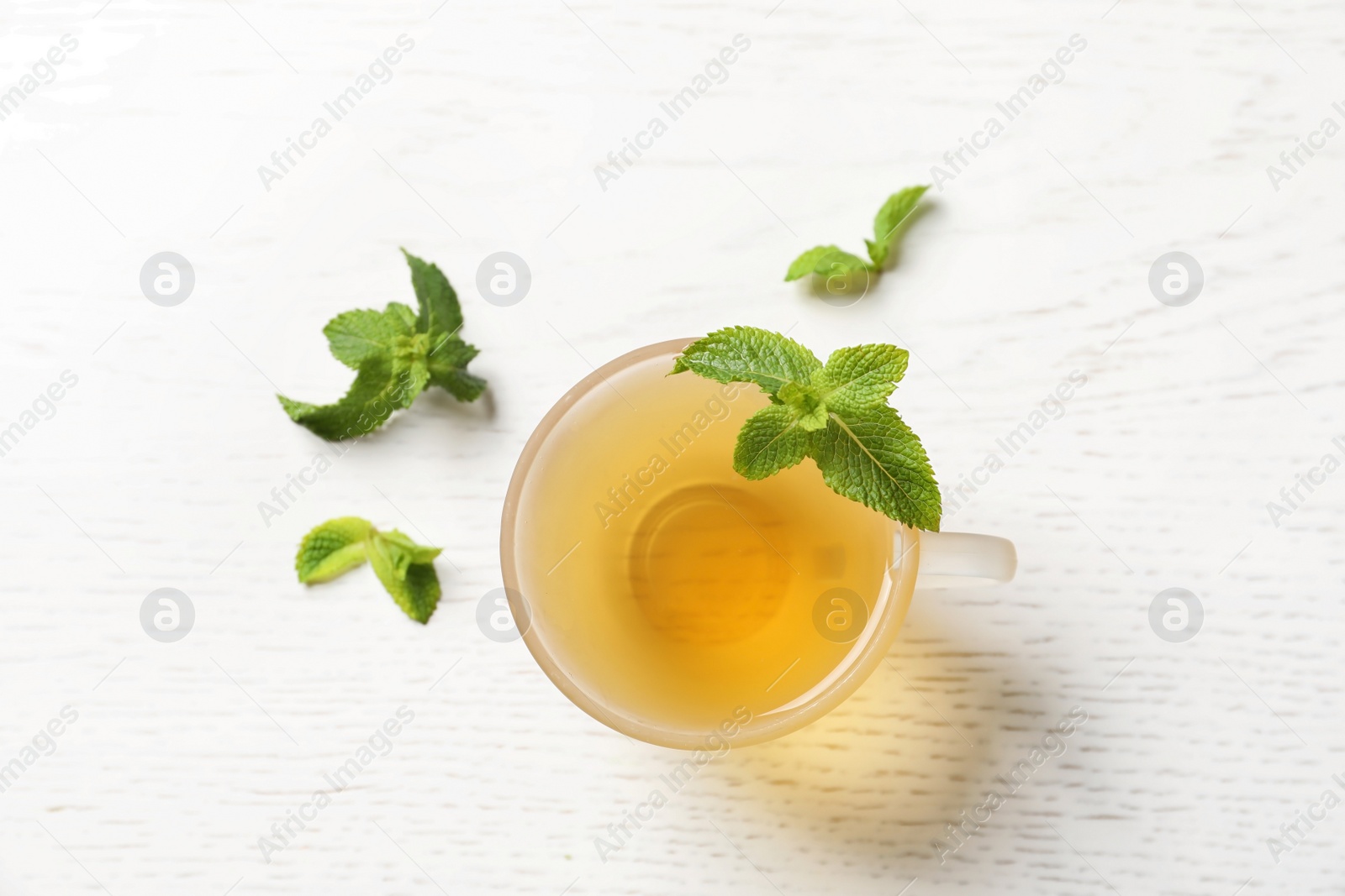Photo of Cup with hot aromatic mint tea and fresh leaves on table, top view
