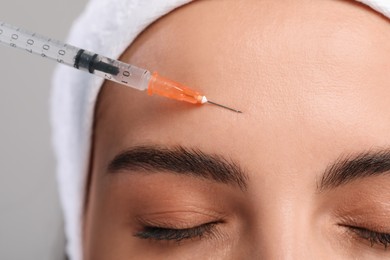 Photo of Young woman getting facial injection on light grey background, closeup. Cosmetic surgery