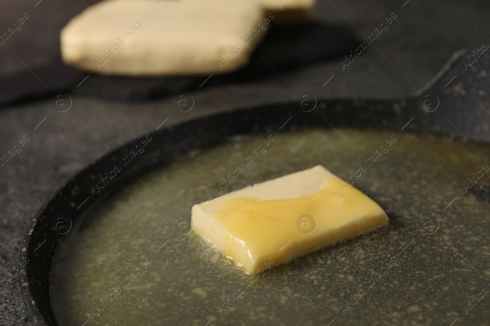 Photo of Melting butter in frying pan on grey table, closeup