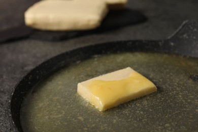 Photo of Melting butter in frying pan on grey table, closeup