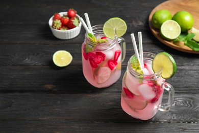 Photo of Mason jars with delicious refreshing drink on black wooden table