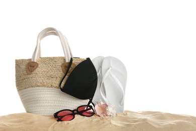 Photo of Stylish bag and different beach accessories on sand against white background