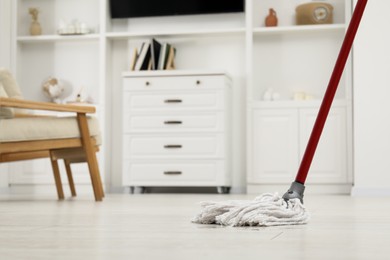 Photo of Cleaning white parquet floor with mop in room. Space for text