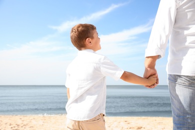 Photo of Little boy with grandfather on sea beach, closeup