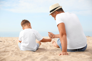 Grandfather with little boy on sea beach in summer