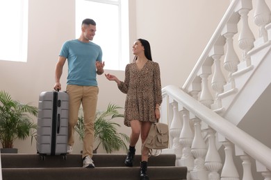 Photo of Happy couple with suitcase going down stairs in hotel