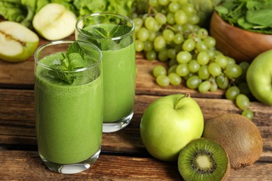 Green smoothie in glasses and fresh ingredients on wooden table