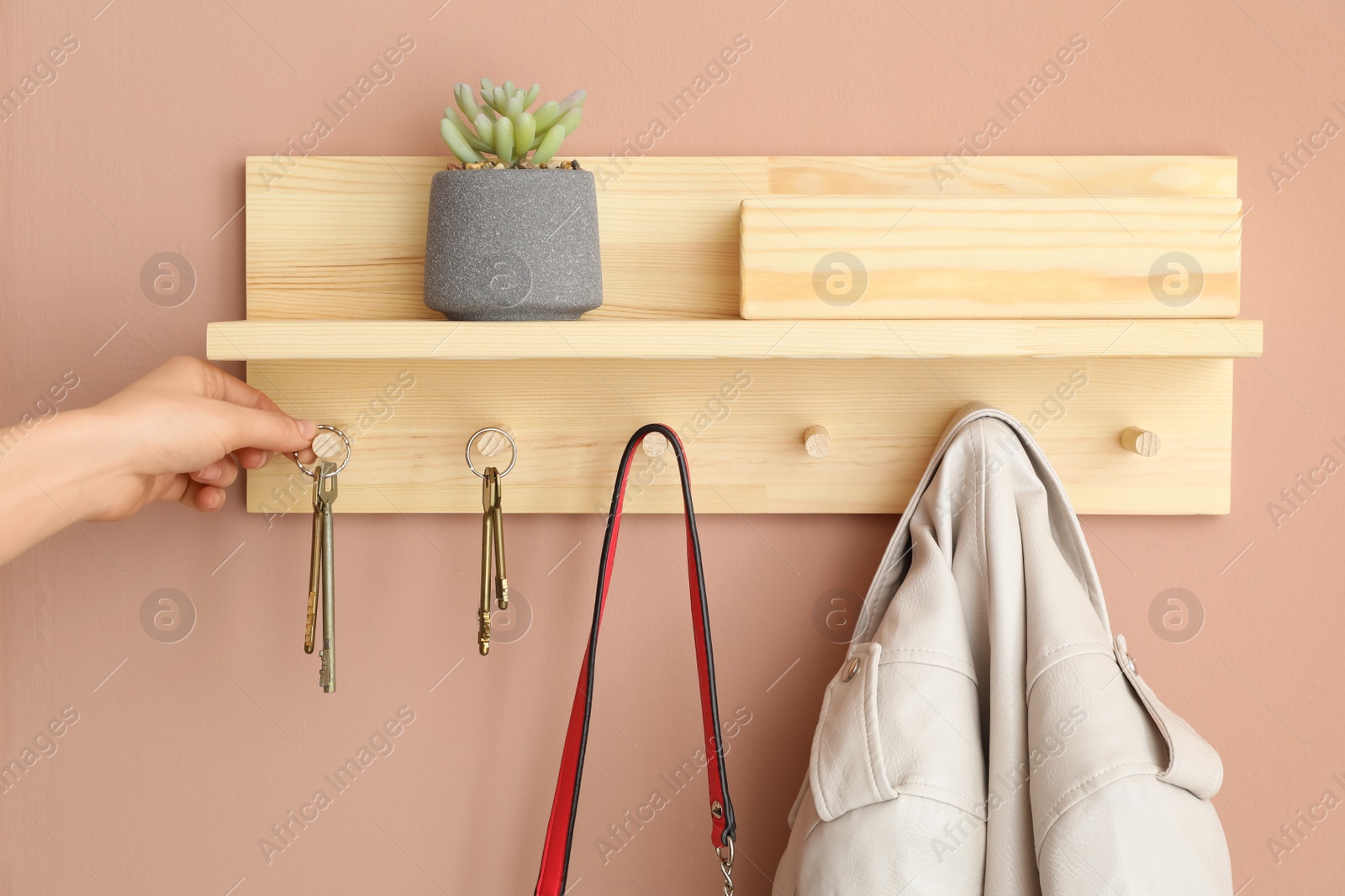 Photo of Woman taking keys from hanger in hallway, closeup