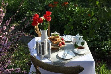 Beautiful bouquet of tulips and freshly baked waffles on table served for tea drinking in garden