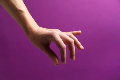 Woman holding something in hand on purple background, closeup