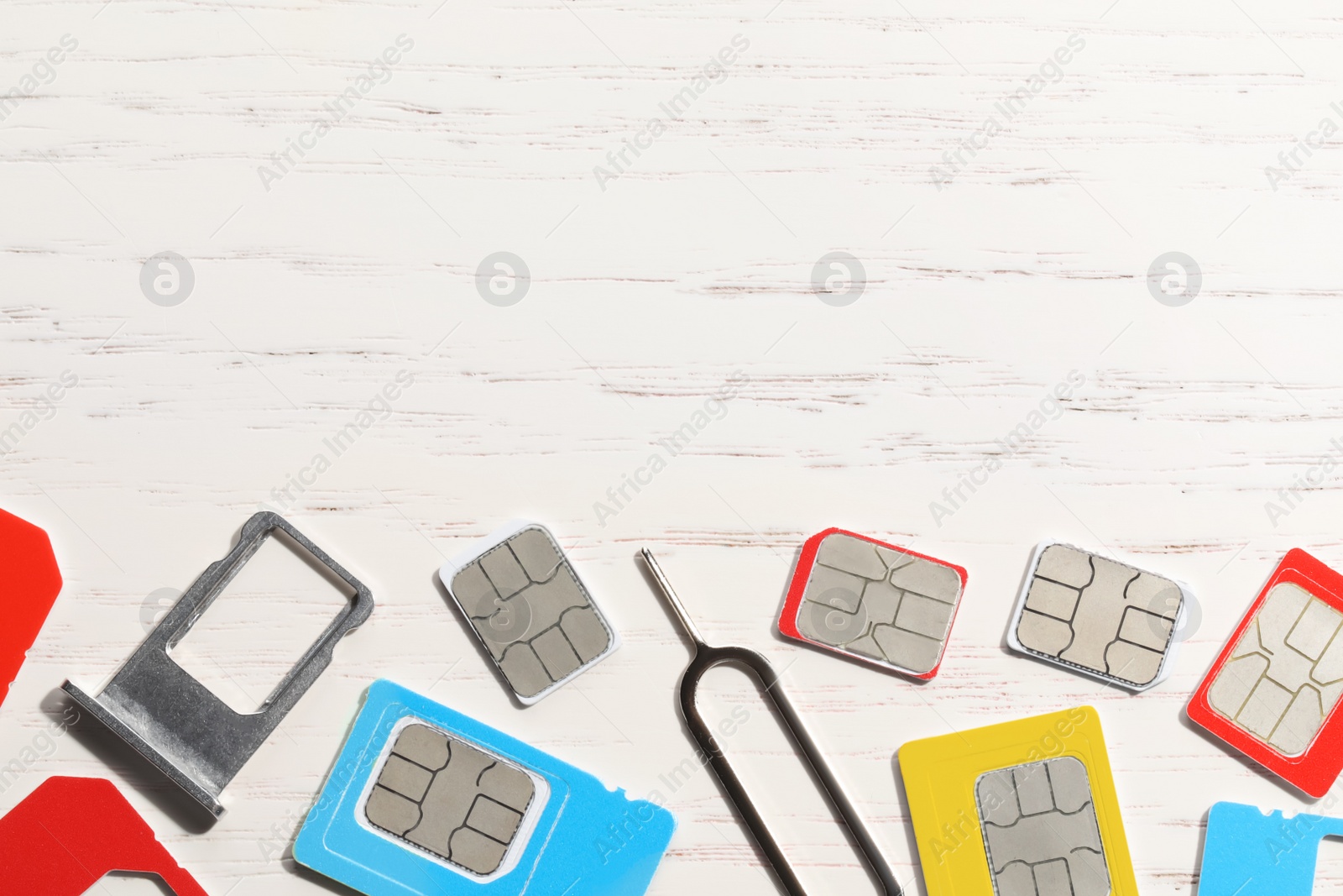 Photo of Different SIM cards, ejector and tray on  white wooden background, flat lay. Space for text