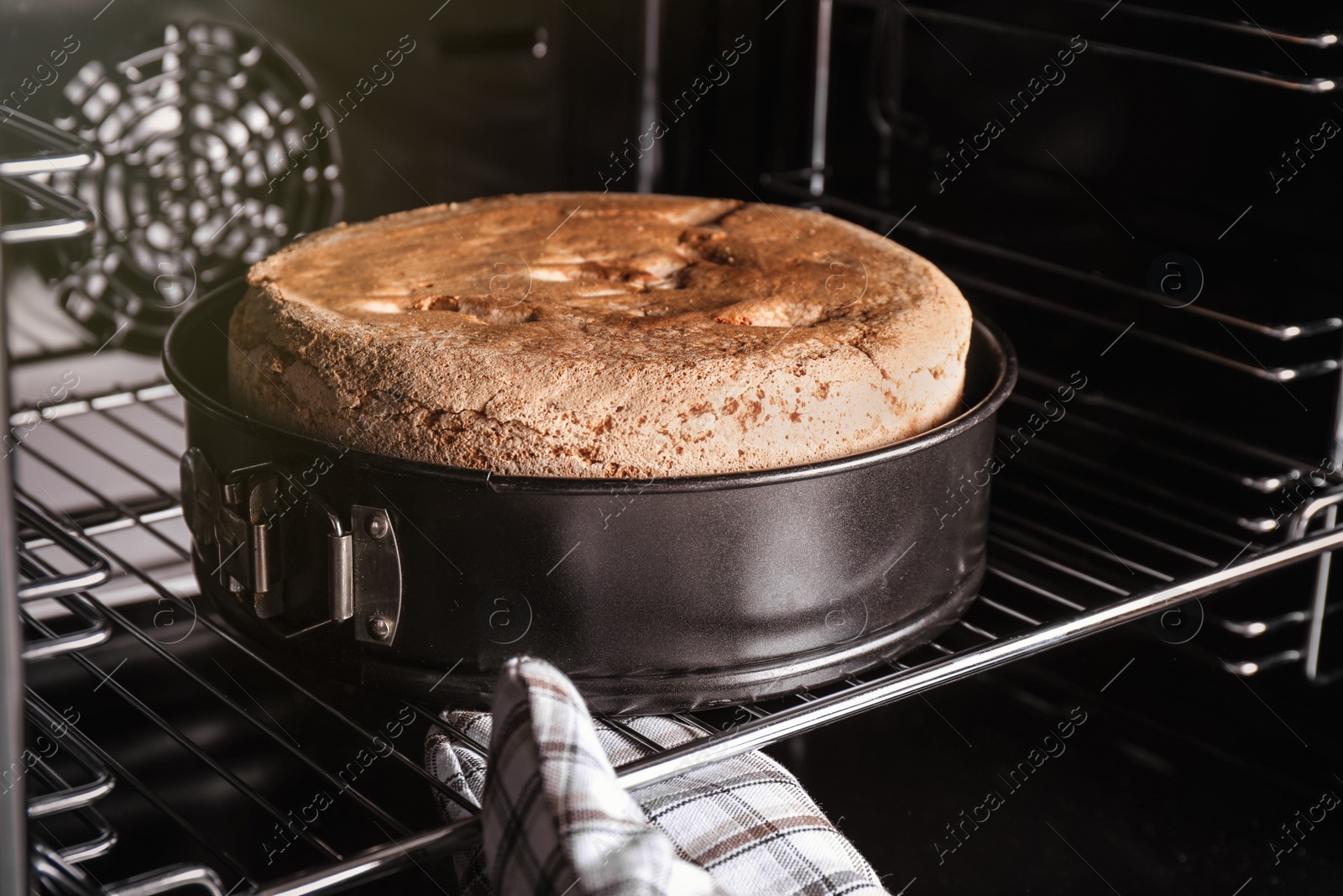 Photo of Person taking delicious fresh homemade cake from oven, closeup