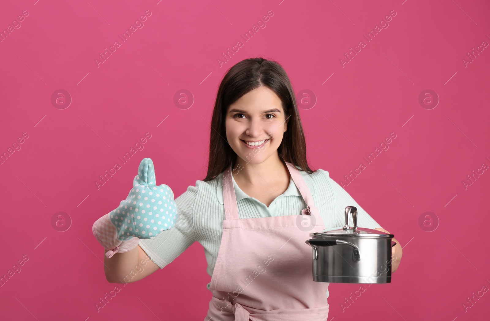 Photo of Happy young woman with cooking pot on pink background