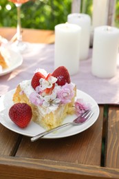 Photo of Piece of delicious homemade cake decorated with fresh strawberries and candles on table outdoors, closeup