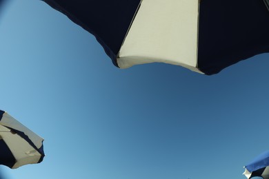 Photo of Beach umbrella against blue sky on sunny day, bottom view