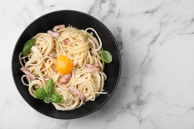 Photo of Delicious pasta Carbonara with egg yolk on white marble table, top view. Space for text