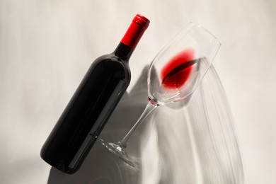 Photo of Bottle of expensive red wine and wineglass on light grey background, top view