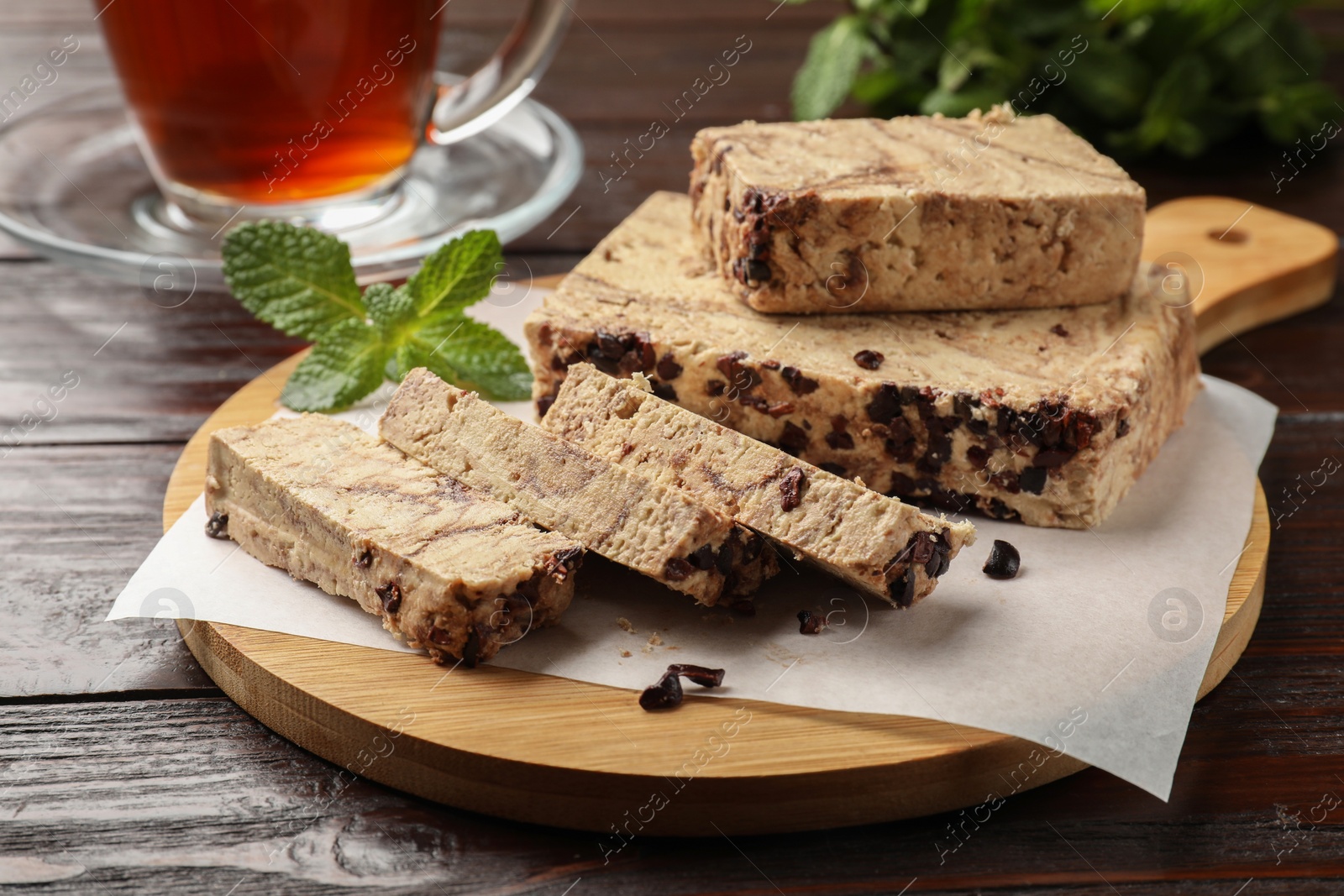 Photo of Pieces of tasty chocolate halva with mint on wooden table, closeup