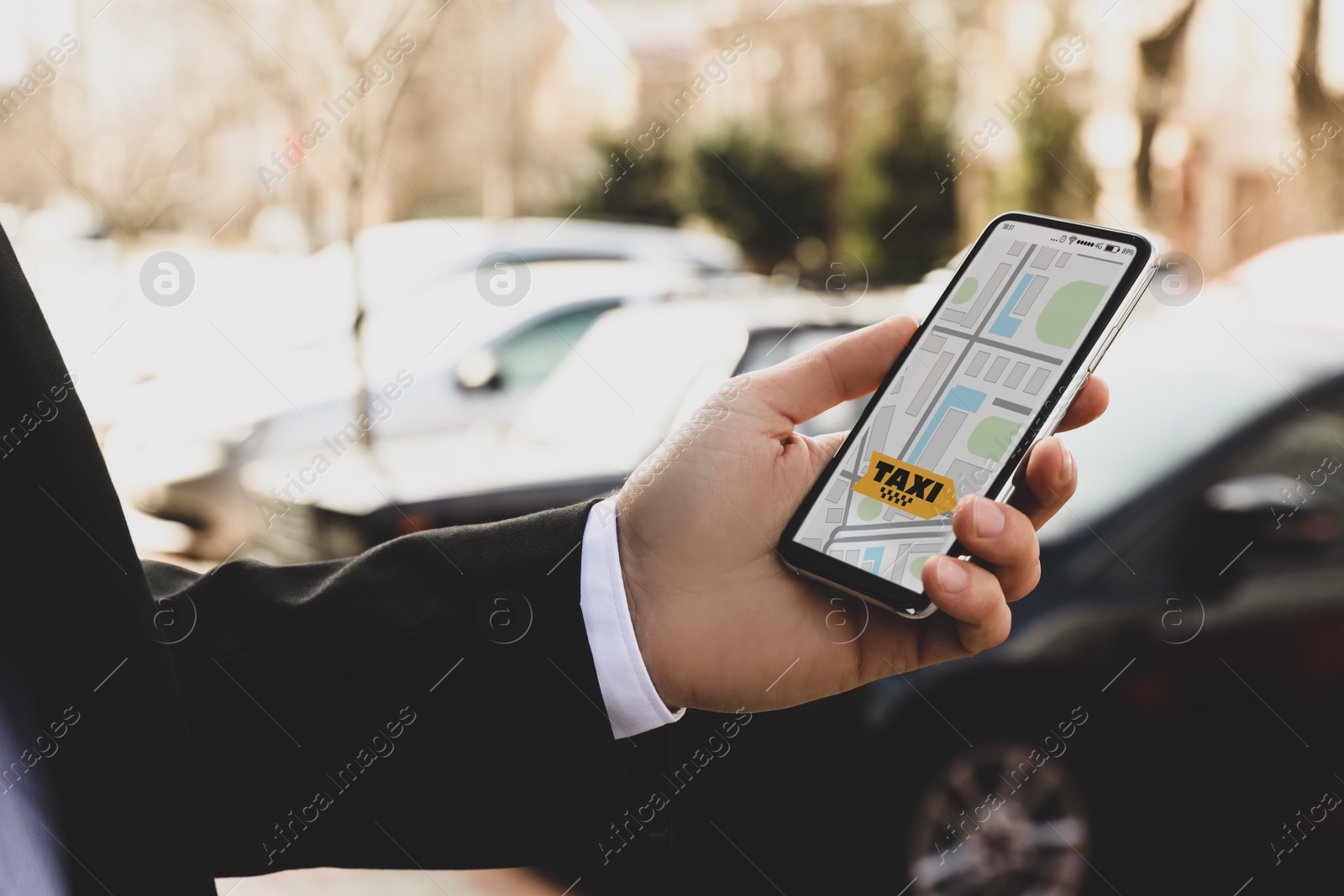 Photo of Businessman ordering taxi with smartphone on city street, closeup