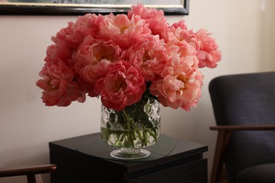 Beautiful pink peonies in vase on nightstand indoors