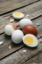 Photo of Hard boiled eggs and pieces of shell on wooden table