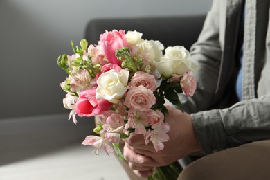 Man holding bouquet of beautiful flowers indoors, closeup