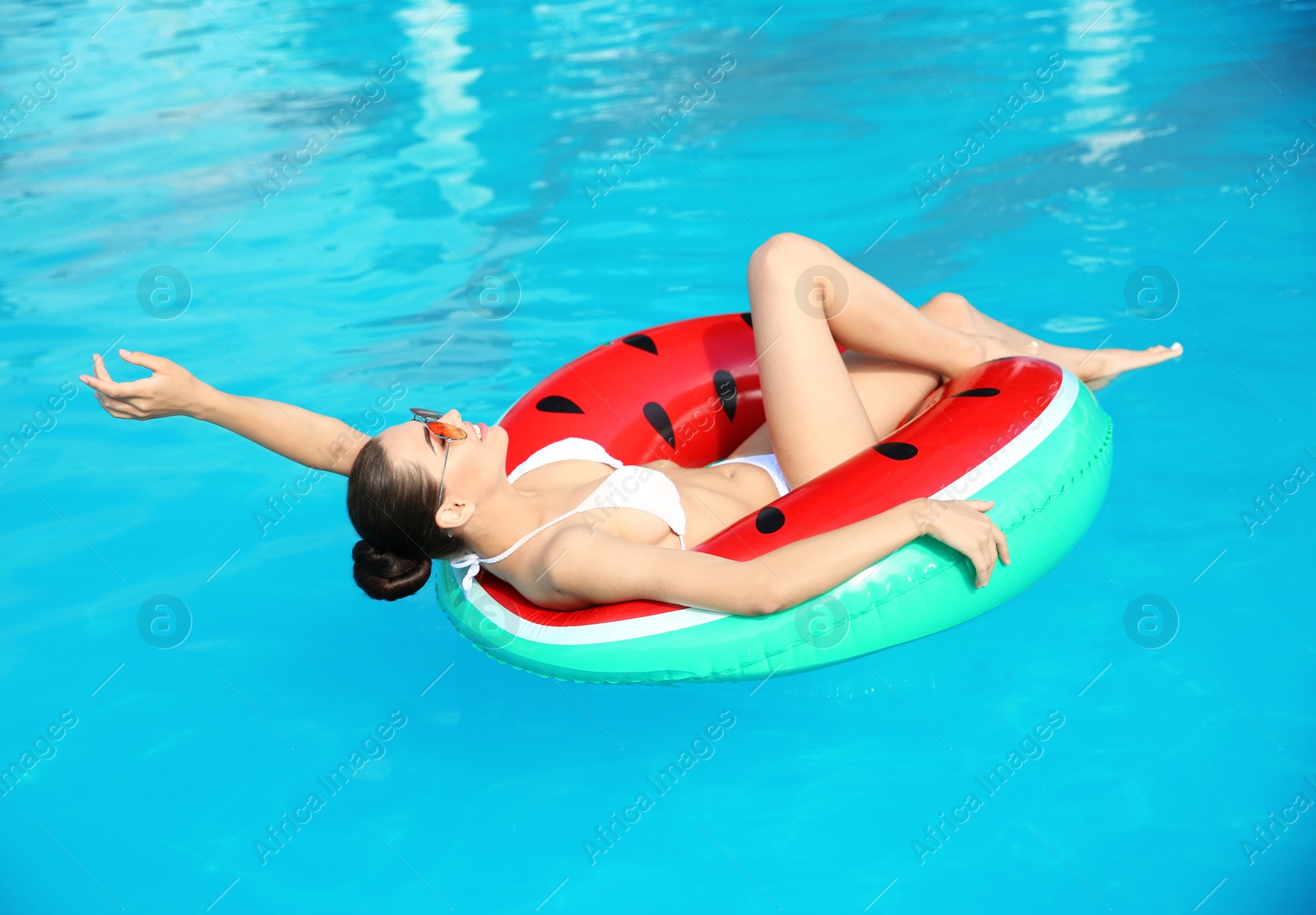 Photo of Beautiful young woman wearing bikini on inflatable ring in swimming pool