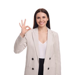 Photo of Beautiful happy businesswoman in suit showing OK gesture on white background