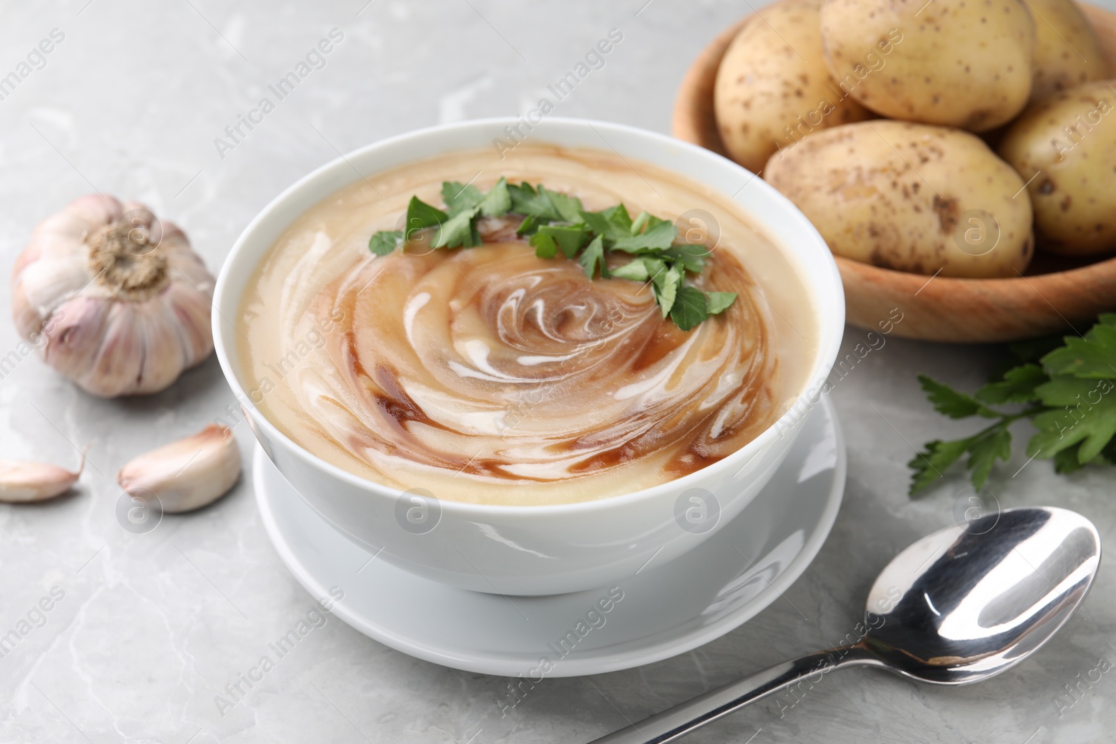 Photo of Delicious cream soup with soy sauce and parsley served on light grey marble table