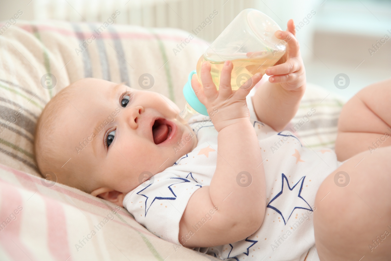 Photo of Pretty baby drinking from bottle on bed at home