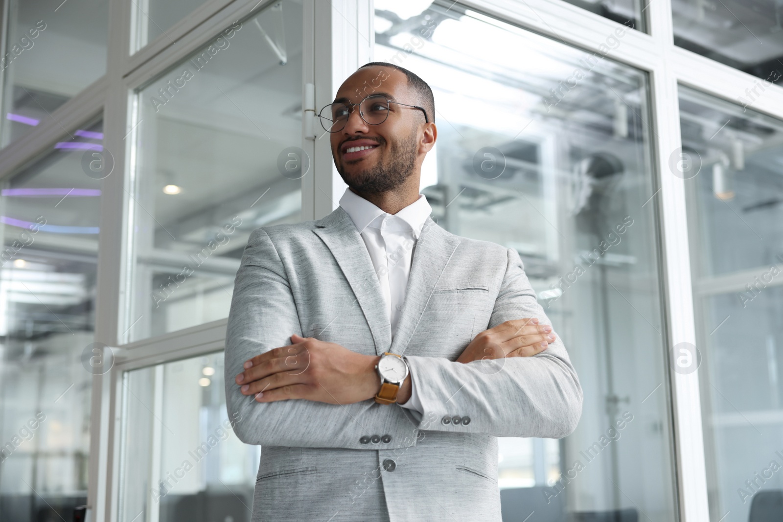 Photo of Happy man with crossed arms in office, low angle view. Lawyer, businessman, accountant or manager