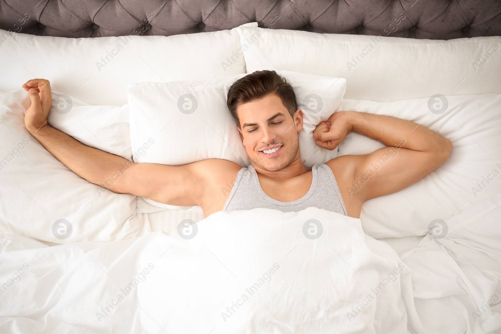 Photo of Man awakening in bed at home, top view. Lazy morning