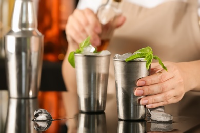 Bartender preparing delicious mint julep cocktail at table