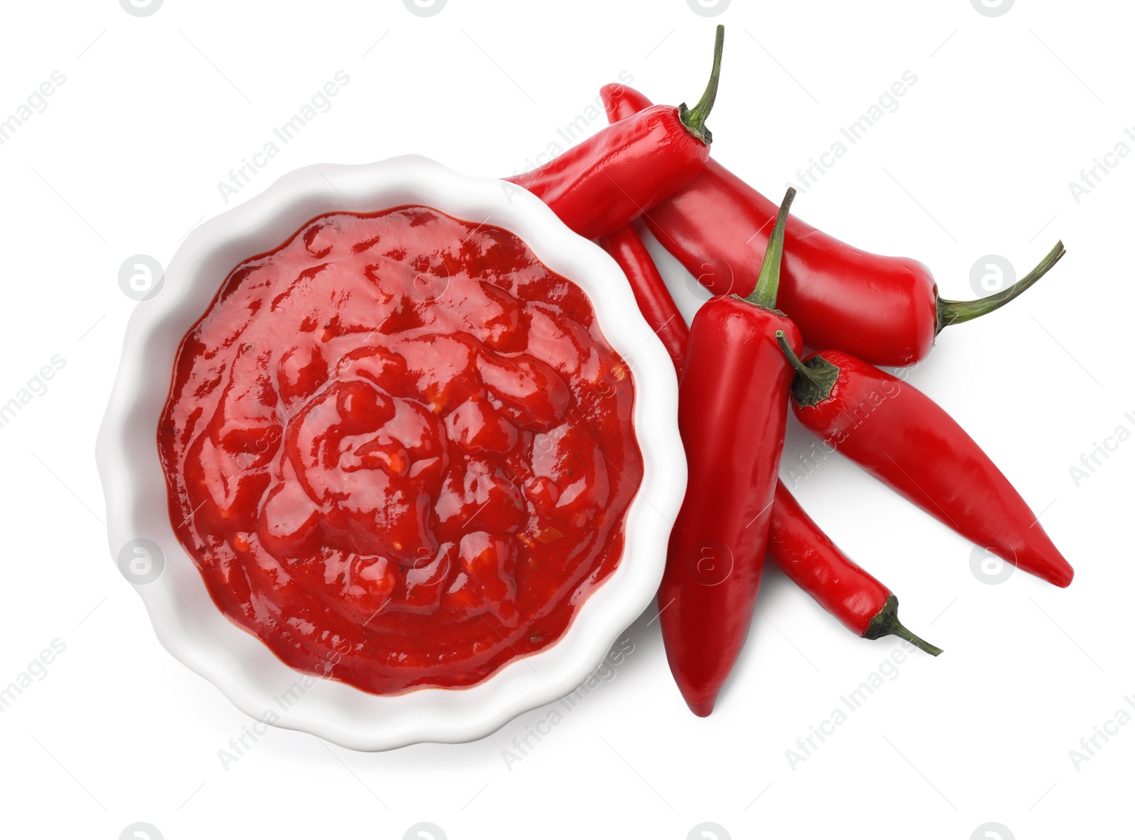 Photo of Bowl with red sauce and fresh chili peppers isolated on white, top view