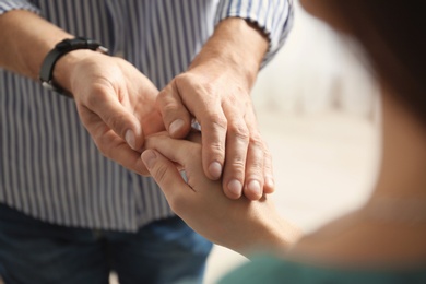 Photo of Man comforting woman on light background, closeup of hands. Help and support concept