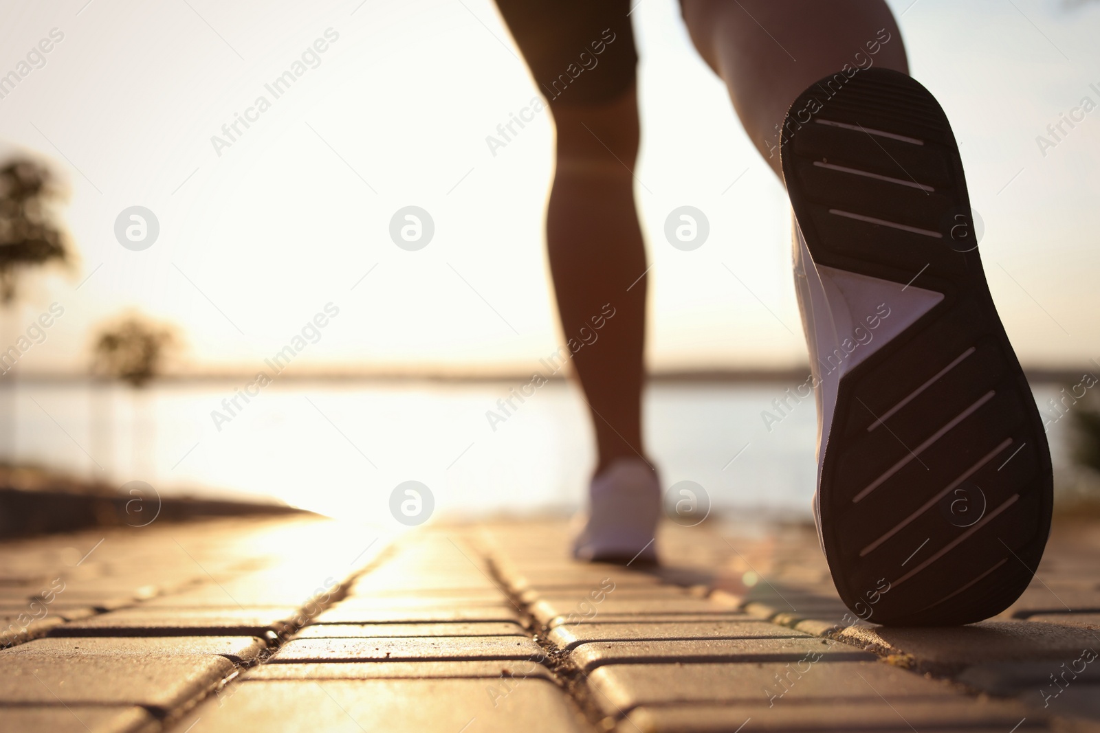 Photo of Young woman running near river in morning, closeup. Space for text