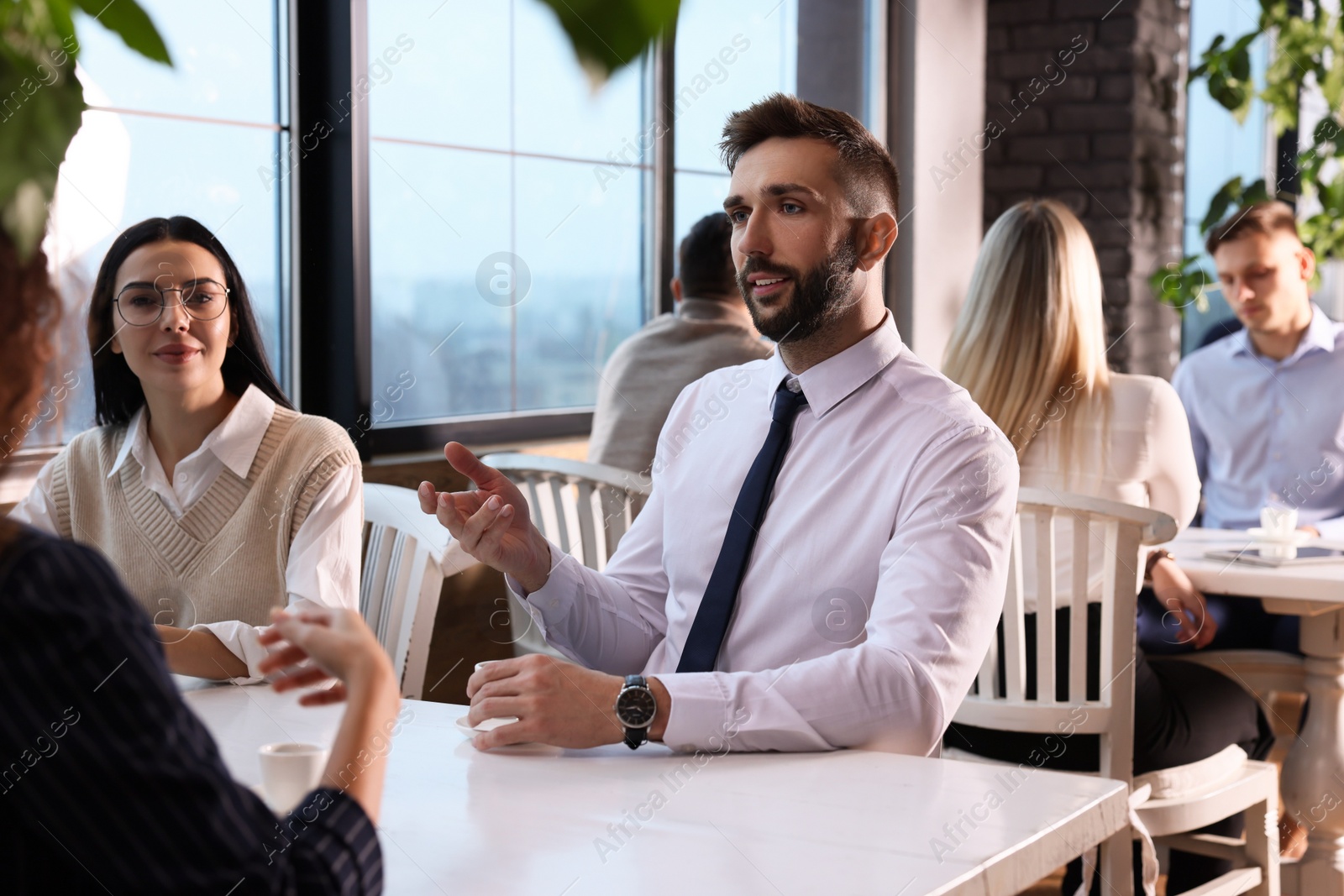 Photo of Coworkers having coffee break near window in cafe