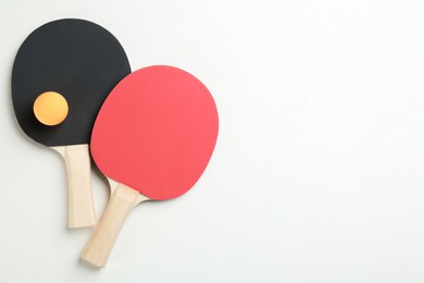 Photo of Ping pong rackets and ball on white table, flat lay. Space for text