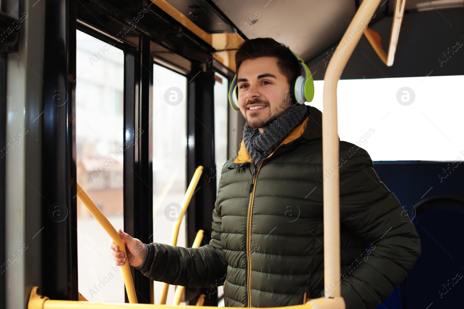 Photo of Young man listening to music with headphones in public transport