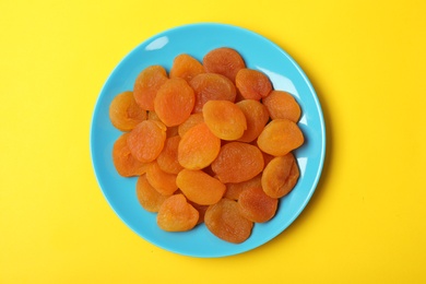 Photo of Plate with dried apricots on color background, top view. Healthy fruit