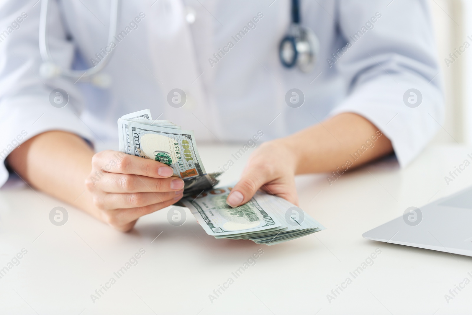 Photo of Doctor with bribe at desk in clinic, closeup. Corrupted medicine