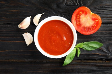 Photo of Flat lay composition with bowl of tomato sauce on wooden table