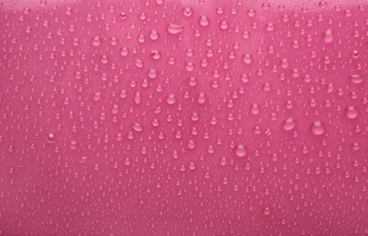 Photo of Water drops on pink background, top view