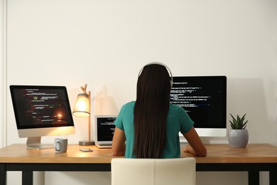 Photo of Programmer with headphones working at desk in office