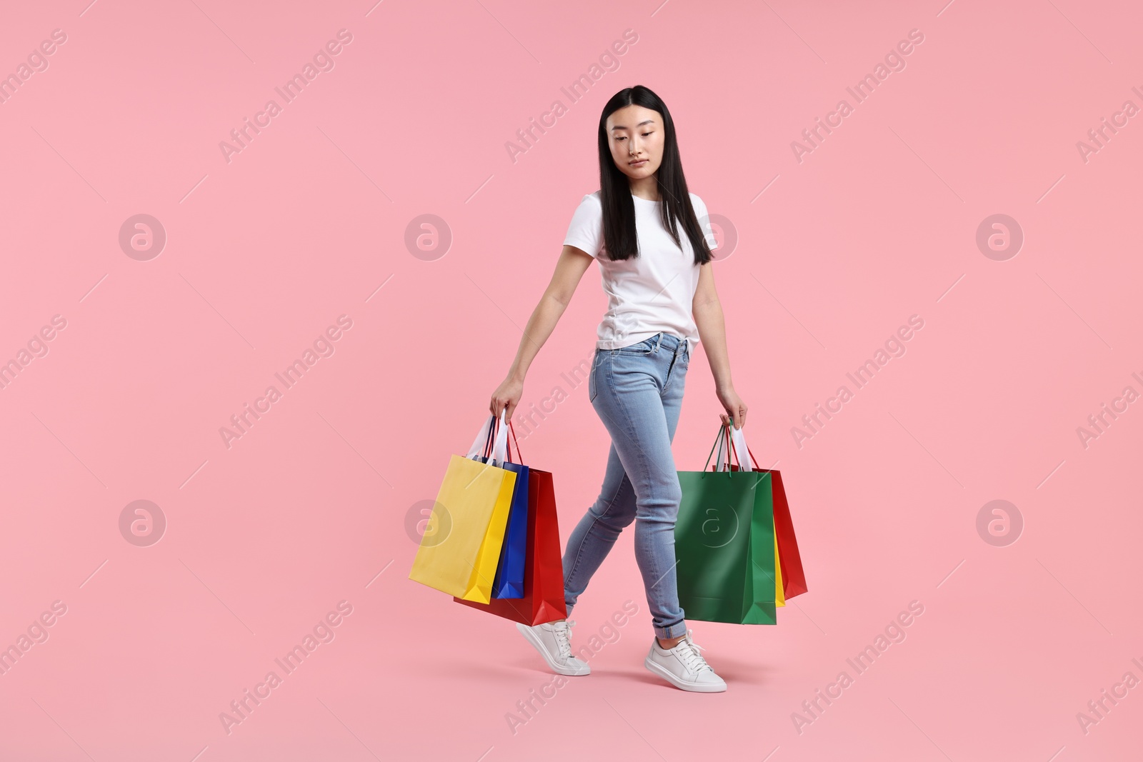 Photo of Beautiful woman with shopping bags on pink background. Space for text