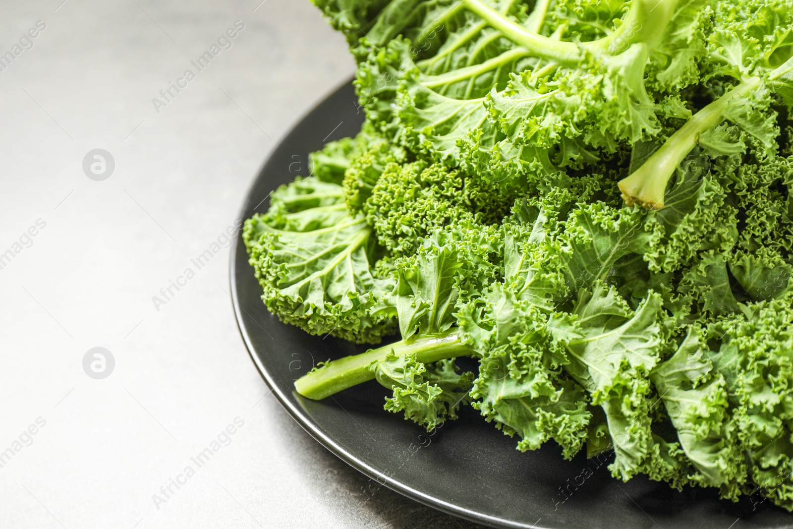 Photo of Fresh kale leaves on grey table, closeup