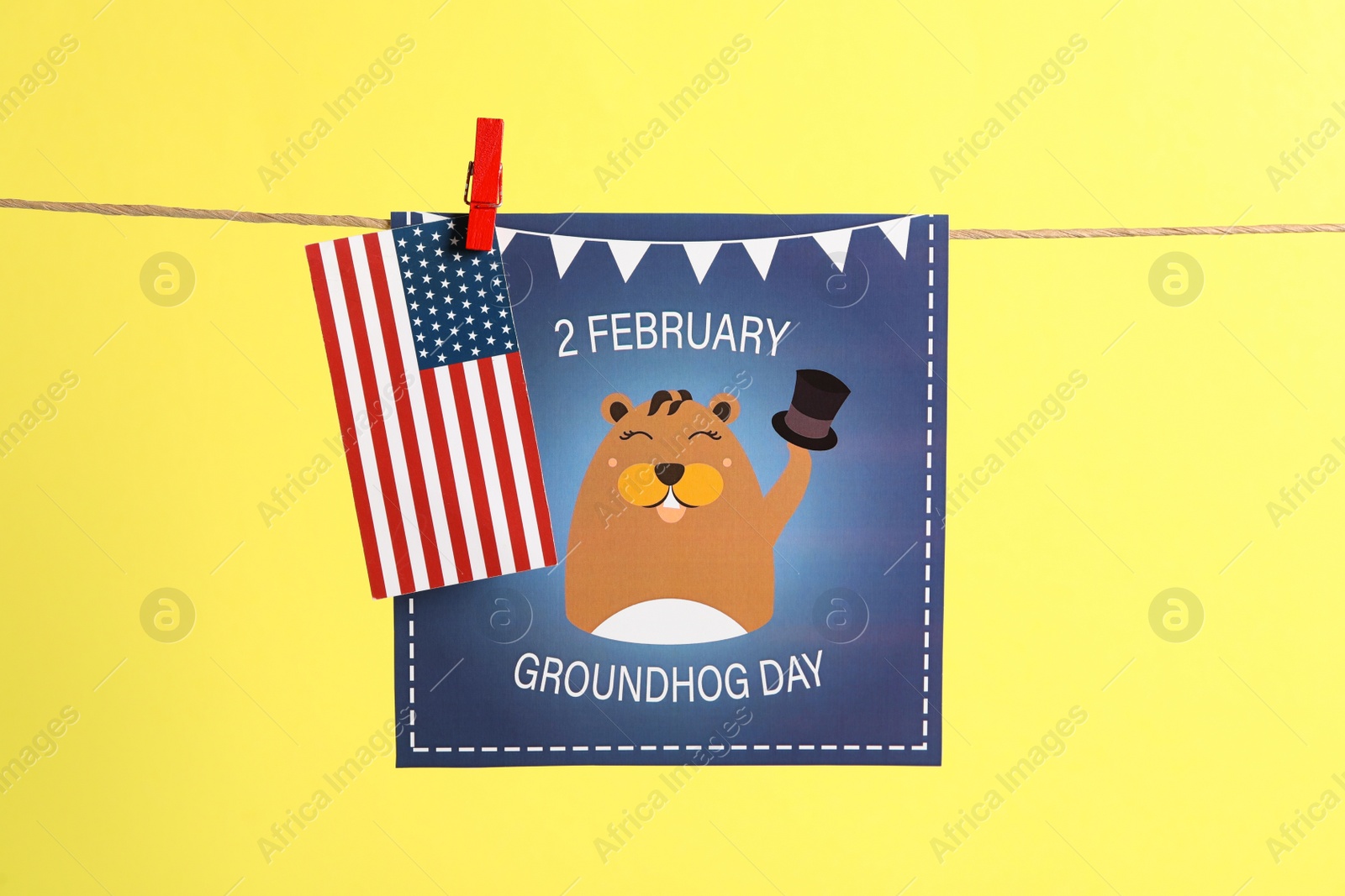 Photo of Happy Groundhog Day greeting card and American flag hanging on yellow background