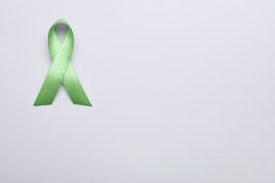 Photo of World Mental Health Day. Green ribbon on white background, top view with space for text