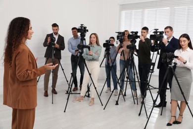 Photo of Happy African American business woman talking to group of journalists indoors